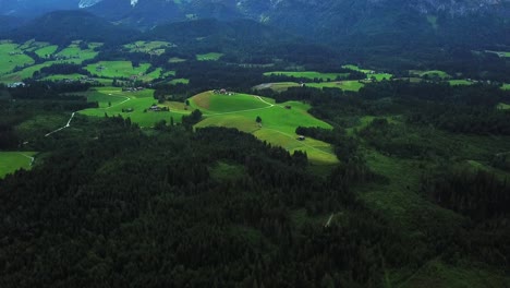 Aerial-view-above-a-mountain-valley-near-Oberndorf,-Austria,-surrounded-by-green-forest
