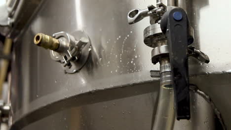 Close-up-shot-of-worker-in-beer-factory-opening-tube-for-fresh-brewed-beer