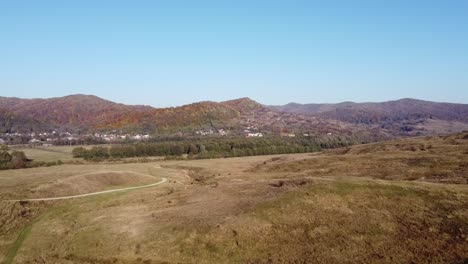 Luftaufnahme-über-Dem-Epischen-Bunten-Herbstwald-Und-Einem-Ländlichen-Dorf-An-Einem-Sonnigen-Tag