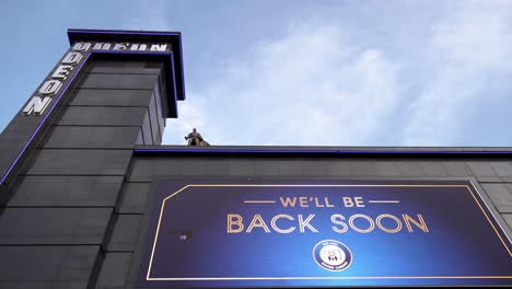 A-Batman-statue-stands-over-a-large-billboard-sign-displaying-warning-messages-and-says-“We’ll-be-back-soon”-at-the-Odeon-cinema-in-Leicester-Square-during-the-second-national-Coronavirus-lockdown