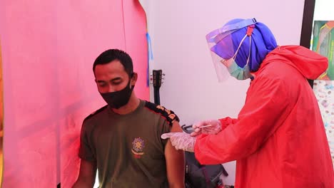 very-noise-and-film-grain-clip,-doctor-holding-syringe-and-using-cotton-before-make-injection-to-patient-in-medical-mask-Covid-19-or-coronavirus-vaccine,-Pekalongan,-Indonesia,-Februari-11,-2021