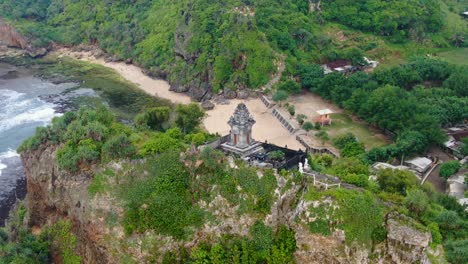Serene-aerial-view-on-Buddhist-temple-on-cliff-by-Ngobaran-beach,-Indonesia
