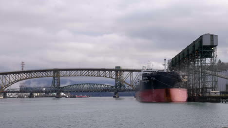 Time-lapse-of-cars-crossing-bridge-over-canadian-Fjord-and-docking-large-container-ship-at-Vancouver-Port