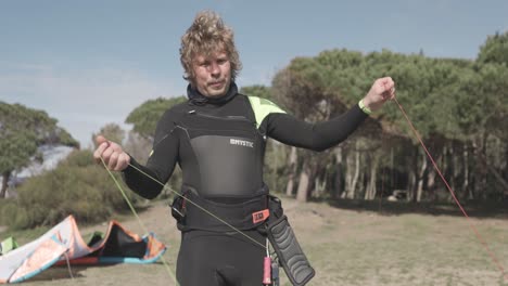 Male-Kiteboarder-In-Wetsuit-Extending-Lines-Of-A-Kite-By-Walking-Upwind-In-Summer