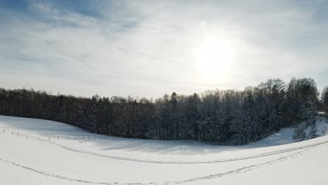 Timelapse-of-a-winter-landscape-in-wide-view-at-a-sunny-day-with-moving-clouds-and-trails-in-the-fallen-snow