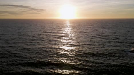 Aerial-view-of-California-sunset-over-the-horizon,-wide-forward-tilt-up-reveal