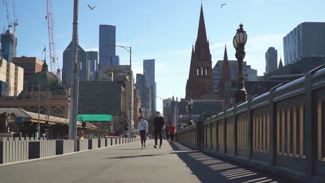 A-couple-wearing-masks-walk-through-Melbourne-during-the-coronavirus-lockdown---COVID-19-outbreak-Australia