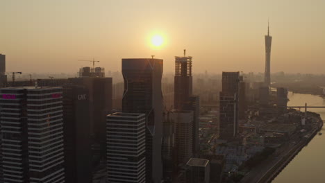 Fly-by-construction-site-of-Alibaba-Group-office-bulding-district-on-bank-of-Pearl-river-at-colorful-golden-sunset-with-Canton-tower-in-far-distance