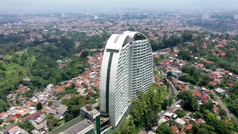 The-Maj-Meliá-Bandung-Dago-Apartment-buildings-with-urban-homes-surrounding-it,-Aerial-orbit-around-shot