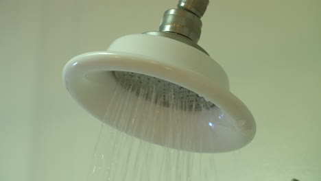 Slow-motion-medium-closeup-of-a-shower-as-the-water-turns-on,-runs-for-a-moment,-shuts-off-and-then-drips-water