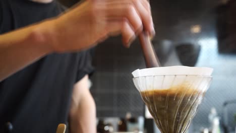 Cinemagraph-of-specialty-coffee-barista-brewing-V60-filter-coffee,-stirring-with-wooden-stick-on-loop