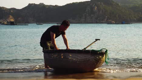 Pescador-Toma-Bote-Coracle-Para-Ir-A-Pescar,-Playa-De-Vinh-Hy-Bay,-Vietnam