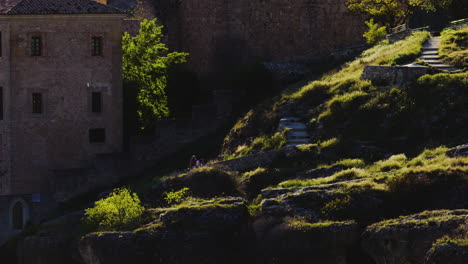 Two-People-Fixing-Grass-Beside-The-Historic-Walled-Town-Of-Cuenca,-Spain---wide-shot