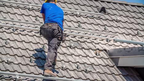Man-holding-drill-working-on-tiles-of-rooftop-hut-during-bright-day