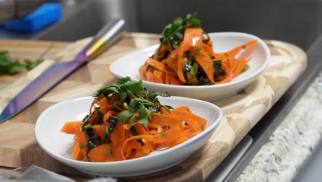 Two-Orange-Pasta-Noodles-Colored-or-Infused-with-Tomato-Paste,-Carrots-or-Chickpeas-Garnished-with-Fresh-Parsley-Sprig-sit-in-Bowls-as-Food-for-Lunch-or-Dinner,-Closeup-in-Restaurant-or-Home-Kitchen