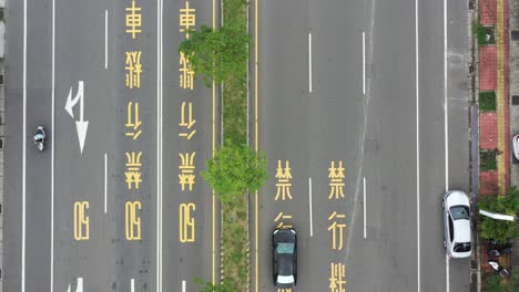 Drohnenaufnahmen-Aus-Der-Luft-Aus-Der-Vogelperspektive-Der-Asphaltierten-Straße-Und-Des-Verkehrs-In-Taiwan-Mit-Chinesischen-Worten,-Die-Beschilderung-Der-Geschwindigkeitsbegrenzung-50-Und-Des-Motorrads-Ist-Auf-Der-Straße-Gemalt-Verboten