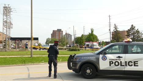 Policeman-barricading-the-area-of-vehicle-accident-with-yellow-tape-and-indicating-to-cameraman-to-go-behind-the-line