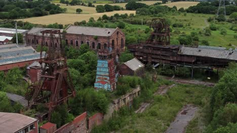 Abandoned-old-overgrown-coal-mine-industrial-museum-buildings-aerial-view-slow-reverse-shot