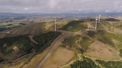 Drohnenflug-Neben-Großen-3-Blatt-Windkraftanlagen-Auf-Dem-Kamm-Eines-Bergrückens-In-Manawatu,-Neuseeland