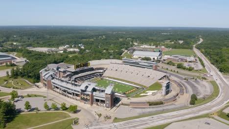 Drone-Flies-Away-from-Mizzou-Stadium,-Faurot-Field-on-Summer-Day