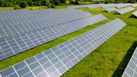 Aerial-close-up-sliding-over-blue-solar-panels-on-green-field-copy-space-template