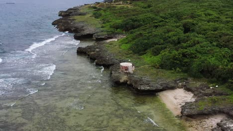 Aerial-drone-pan-shot,-coastline-with-ocean-waves-hitting-the-rocky-shore-in-Xiaoliuqiu-Lambai-Island,-Pingtung-county,-Taiwan