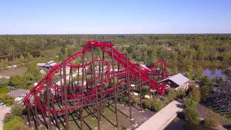 Aerial-parallax-of-red-rollercoaster-and-other-rides-at-amusement-park