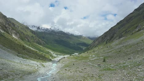 Vuelo-De-Drones-Sobre-Un-Sinuoso-Río-Glaciar-A-Través-De-Un-Valle-Alpino-De-Alta-Montaña