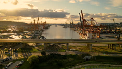 Verkehr-über-Hochstraße-Mit-Containerterminals-Im-Hintergrund-Während-Des-Sonnenuntergangs-Im-Hafen-Von-Gdynia,-Polen