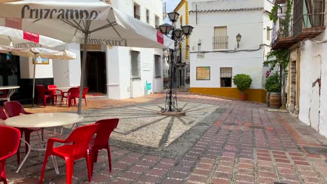 Typical-Spanish-street-in-old-city-Marbella-with-white-houses,-red-chairs-and-restaurants
