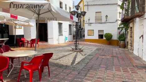 Calle-Típica-Española-En-La-Ciudad-Vieja-De-Marbella-Con-Casas-Blancas,-Sillas-Rojas-Y-Restaurantes