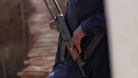 Lower-Half-View-Of-Male-Leaning-Against-Wall-Holding-Kalashnikov-Rifle