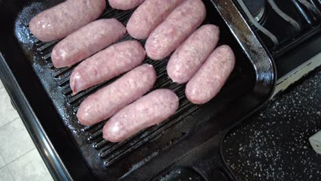 Grilling-raw-sausages-on-stove-top-in-Mexico-City,-Mexico,-wide-shot-top-down