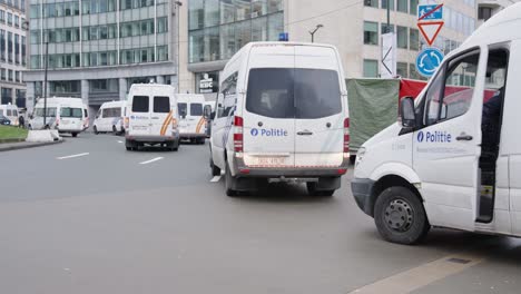 Belgian-police-vans-protecting-Shuman-roundabout-during-anti-corona-riots-in-the-city-of-Brussels,-Belgium---Police-officer-gets-in-the-vehicle