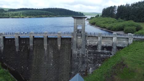 Alwen-reservoir-Welsh-woodland-lake-water-supply-aerial-view-concrete-dam-countryside-park-slow-fly-over-bridge
