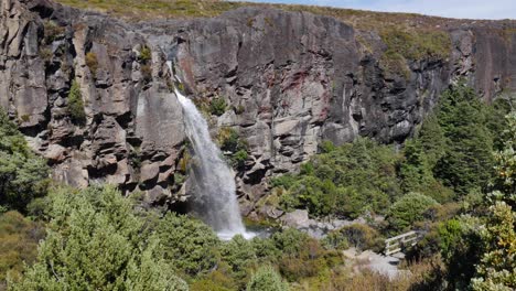 Waterfall-cuts-from-high-plateau-down-rock-cliff-to-hiking-trail-below
