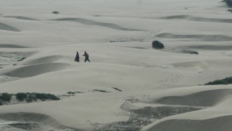 Zwei-Menschen-Gehen-In-Der-Ferne-über-Sanddünen-In-Balochistan