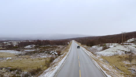Vehicle-Driving-On-Countryside-Road-Of-Dovre,-Innlandet-County,-Norway-During-Winter---aerial-drone-shot
