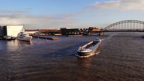 Vista-Aérea-Del-Buque-Portacontenedores-Interior-Fenny-Ii-A-Lo-Largo-Del-Río-Noord-Con-Brug-Over-De-Noord-En-Segundo-Plano