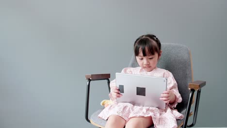 Child-watching-digital-tablet-for-education-at-home-and-looking-at-cheerful-camera