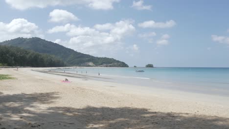 the-beach-with-a-few-yachts-in-sea,-white-sand-and-wave-from-peaceful-sea-in-sunshine-daytime