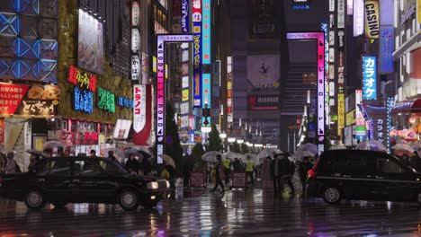 Rainy-night-on-the-Street-of-Kabuki-cho,-Taxis-passing-Bright-Neon-Lights