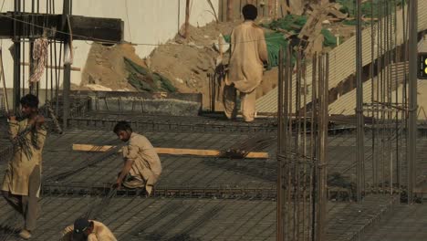 Pakistani-Male-Workers-Carrying-Rebar-On-construction-building-site