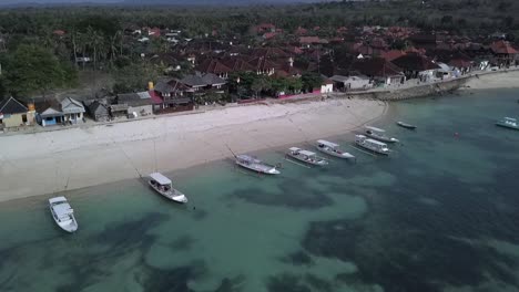 Calmer-aerial-view-flight-panorama-overview-drone-footage-of-a-dream-beach-with-crystal-clear-turquoise-water,-boats-floating-at-paradis-island-lembongan