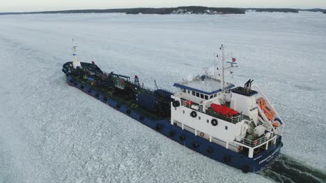 Close-up-aerial-tracking-view-of-oil-and-chemical-tanker-CRYSTALWATER-call-sign-ESLI-moving-ahead-in-ice-covered-Finnish-archipelago