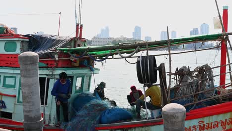 Cuatro-Personas-Arreglando-Redes-Y-Luego-Una-Entra-En-La-Cabaña,-Muelle-De-Pesca-De-Pattaya,-Chonburi,-Tailandia