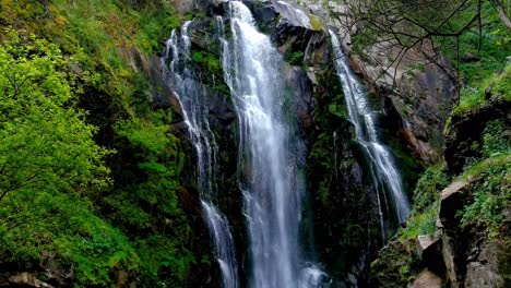 Adult-Male-Wearing-Red-Shorts-Wading-Through-Water-At-Base-Of-Fervenza-do-Toxa-Waterfalls