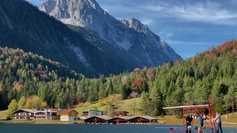 Tilt-shot-of-Lauter-Lake-with-persons-and-peaks-of-the-Karwendel-mountains-in-the-background,-very-close-to-the-bavarian-town-of-Mittenwald-in-Germany