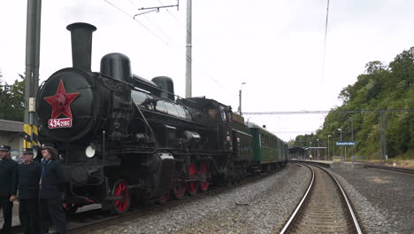 Three-conductors-posing-with-steam-train-standing-in-railway-station