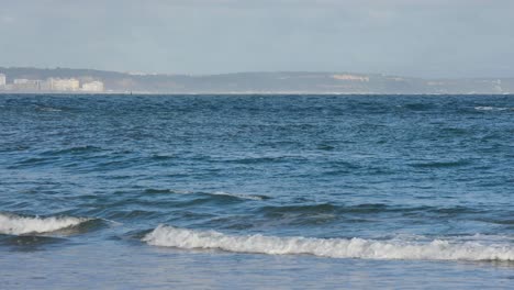 Getting-away-to-the-water-and-to-the-waves-on-a-summer-day-at-Carcavelos-with-Costa-da-Caparica-in-background,-Cascais-beach